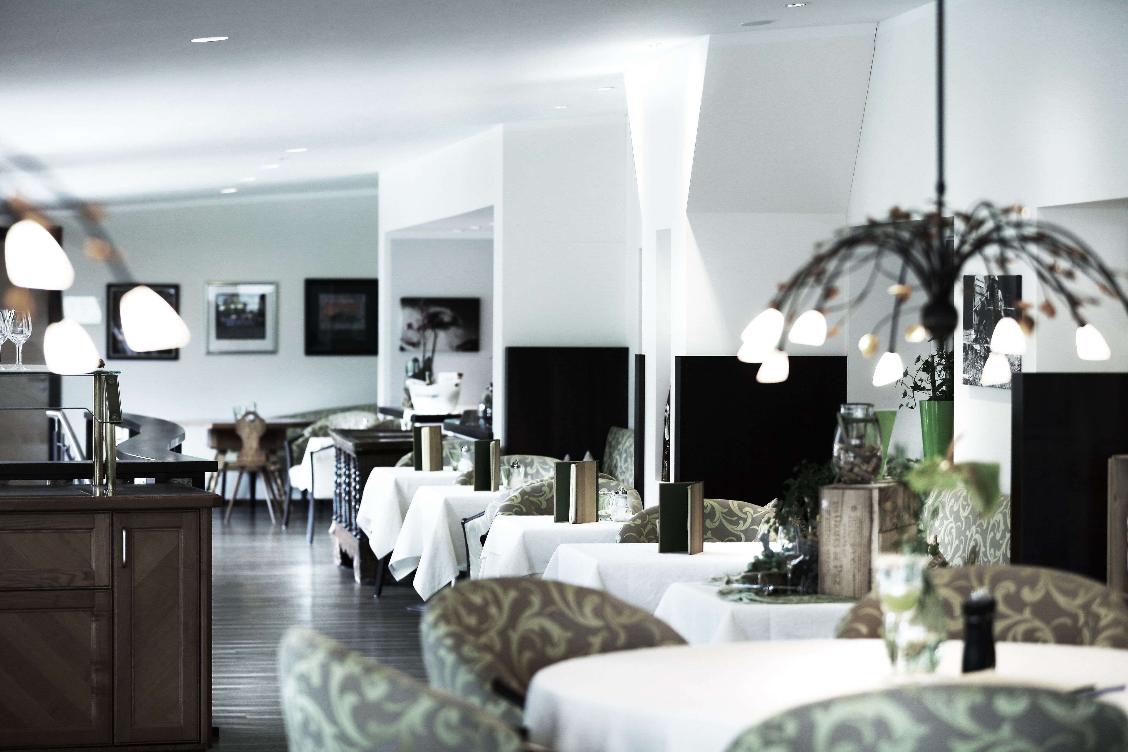 Un'area ristorazione moderna con tavoli apparecchiati, un angolo bar e una zona salotto con rivestimenti decorati.