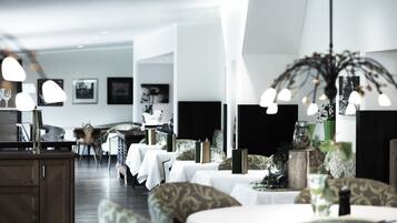 Un'area ristorazione moderna con tavoli apparecchiati, un angolo bar e una zona salotto con rivestimenti decorati.