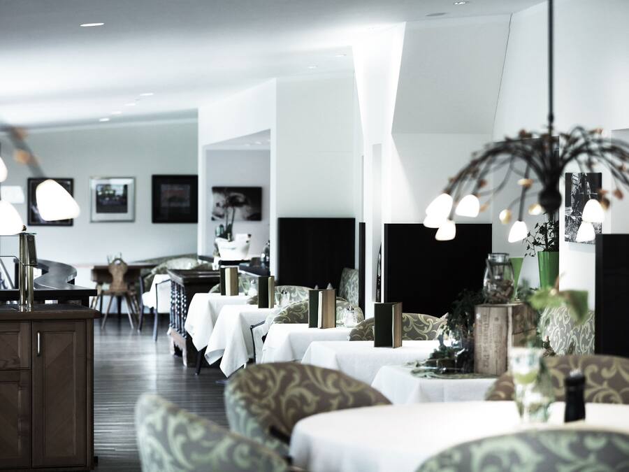 Un'area ristorazione moderna con tavoli apparecchiati, un angolo bar e una zona salotto con rivestimenti decorati.