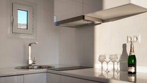 Een moderne keuken met een inbouwspoelbak, een raam en een fles Henkell Trocken wijn met glazen op het aanrecht.