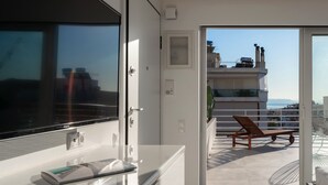 Een modern interieur met een grote flatscreen-tv, een glazen kast en een schuifpui naar een balkon met een stoel en een tafel.