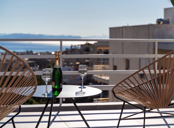 Un balcon avec une table, deux chaises, une bouteille de champagne et deux verres.