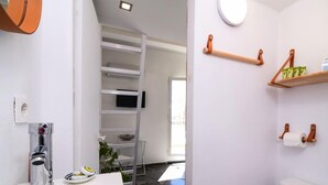 Une salle de bain moderne avec un lavabo blanc, un miroir, un porte-serviettes et un support à papier toilette.