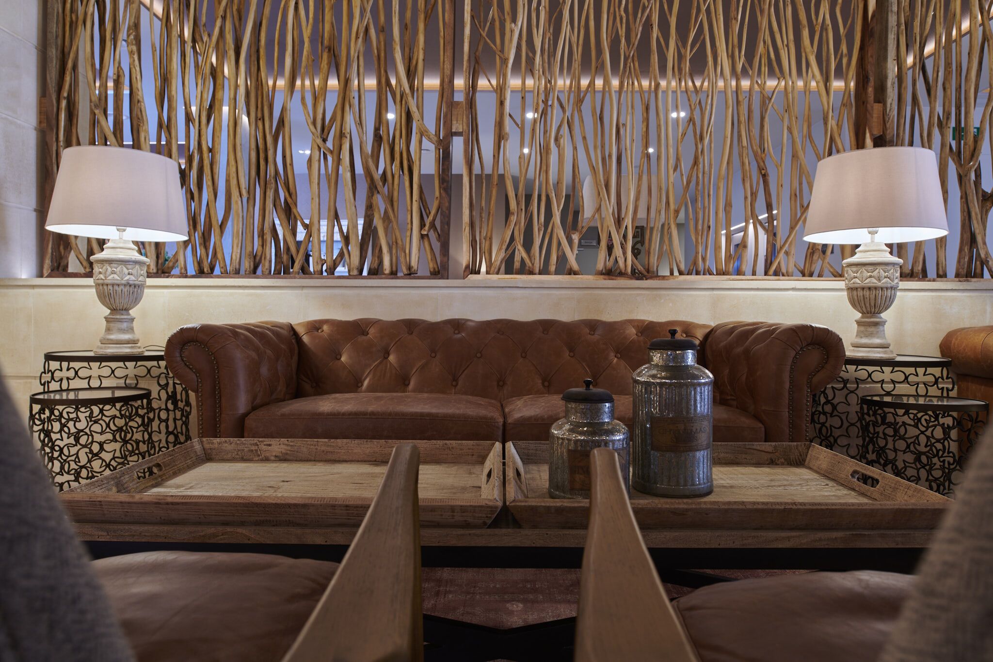 A cozy seating area with a brown leather sofa, two side tables with lamps, and a tray with decorative items.