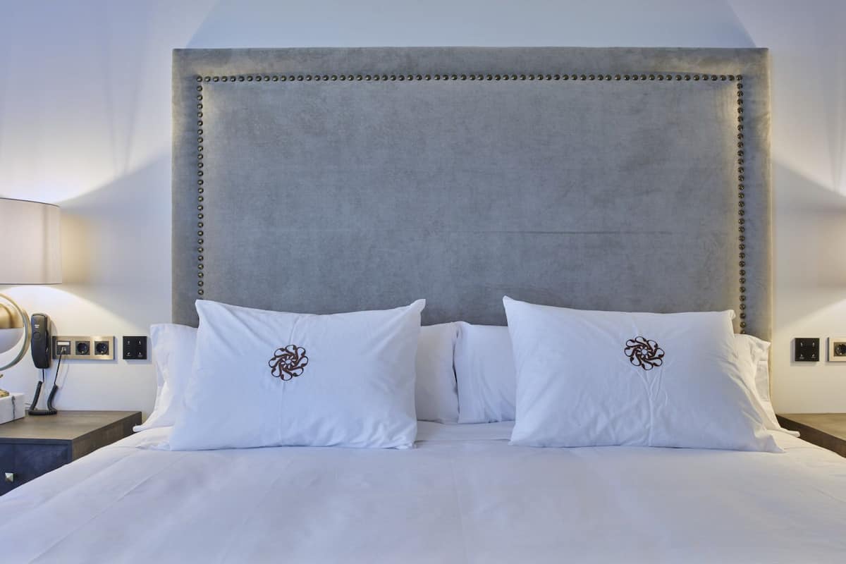 A hotel room with a large bed, two bedside lamps, and a modern headboard.