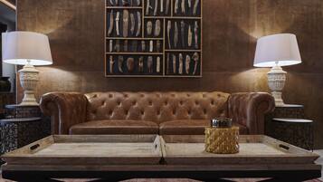 A brown leather sofa with a wooden tray in front, flanked by two side tables with lamps.