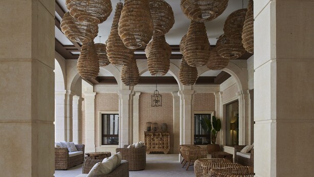 A spacious lobby with wicker furniture, a central chandelier, and a brick wall with windows. - Ansares Hotel (Tarancon)