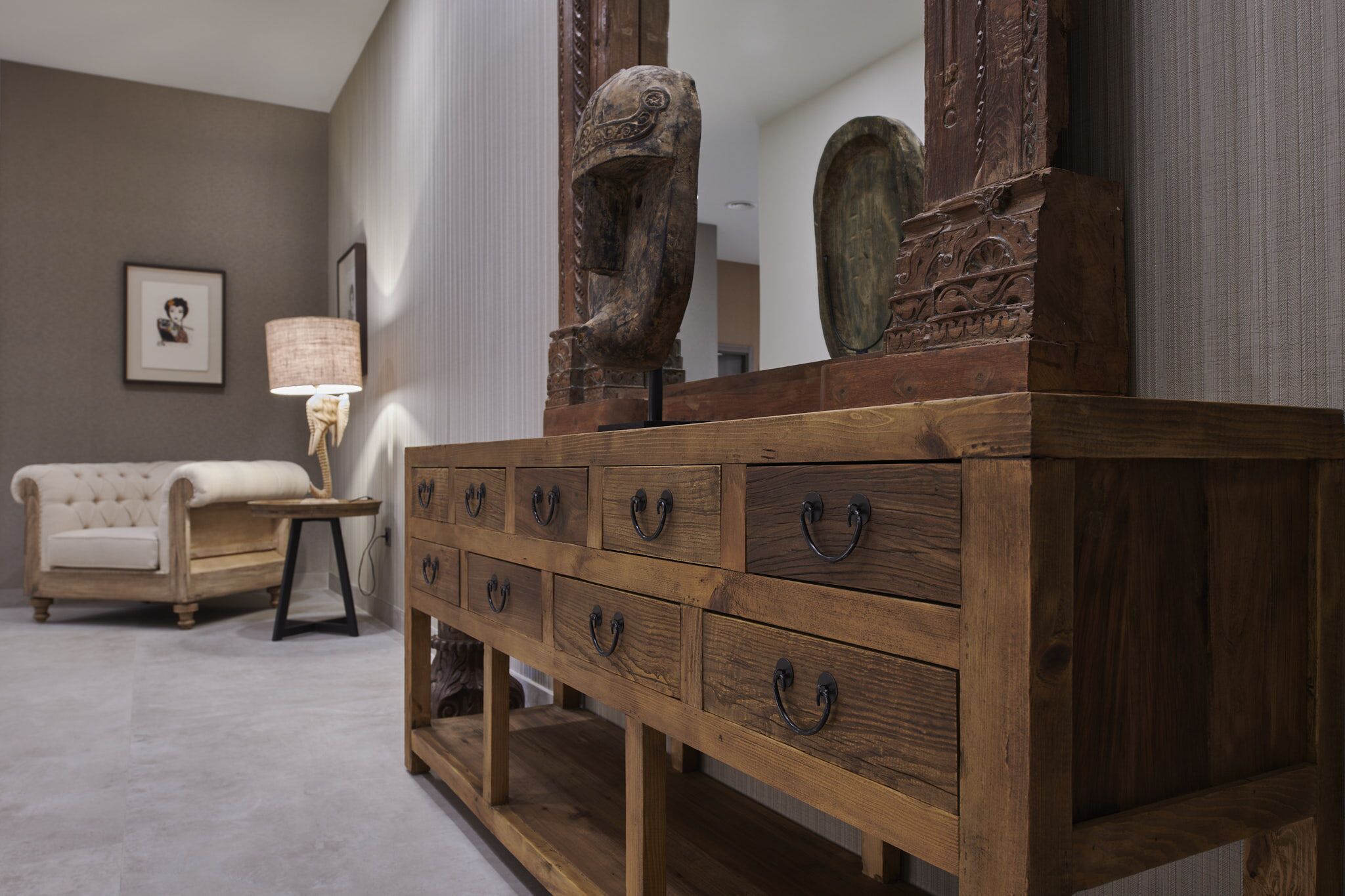 Een houten dressoir met meerdere lades en een grote spiegel erboven.