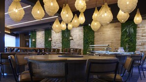 A restaurant with round tables and chairs, hanging light fixtures, and a brick wall with greenery. - Ansares Hotel (Tarancon)
