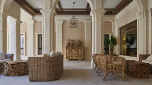 A spacious lobby with high ceilings, arched columns, wicker furniture, and a central decorative piece. - Ansares Hotel (Tarancon)