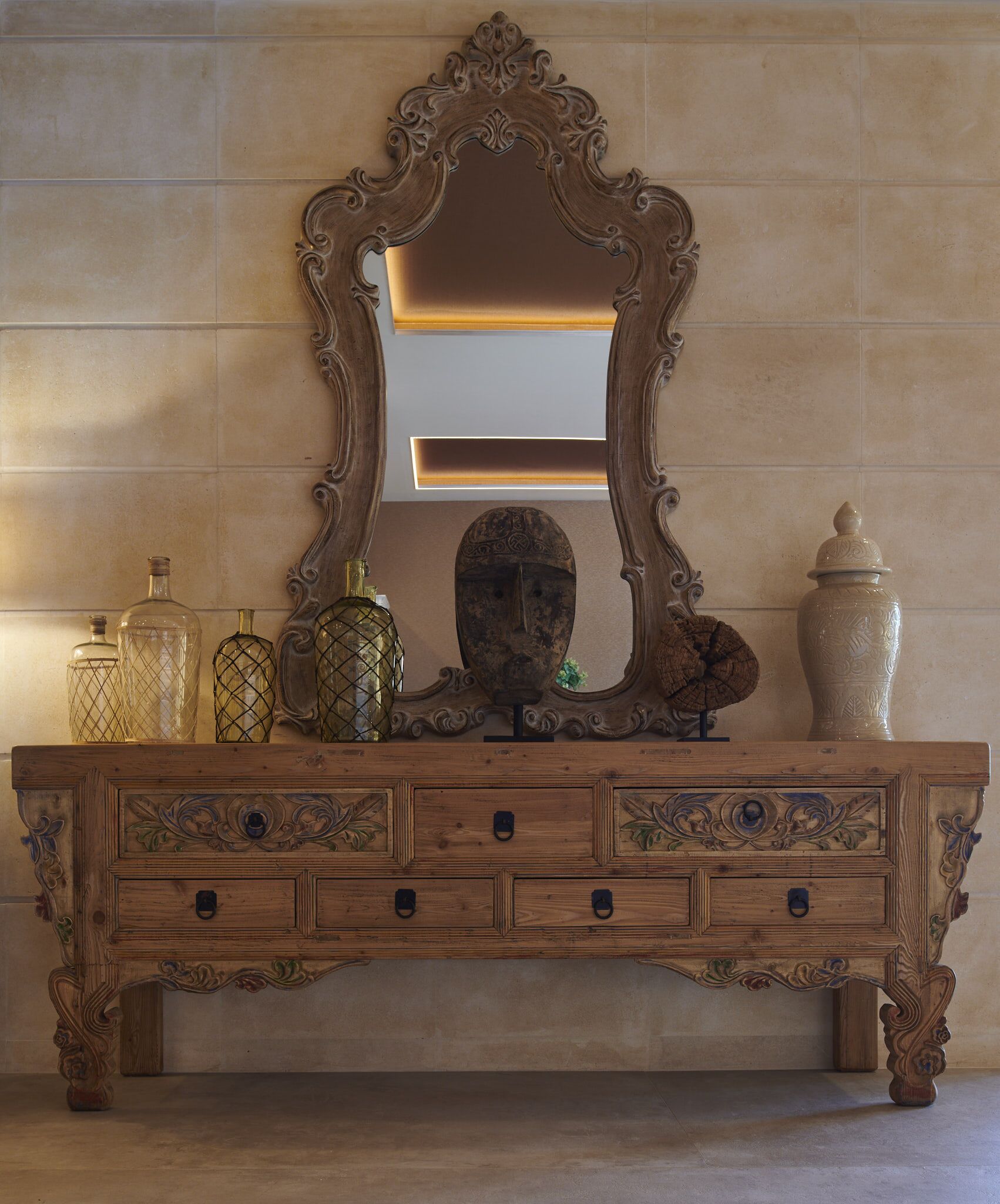 A wooden dresser with ornate carvings and a large mirror above it.