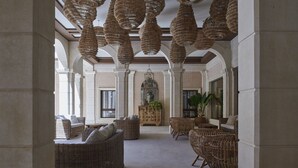 A spacious lobby with wicker furniture, a central planter, and a hanging light fixture. - Ansares Hotel (Tarancon)