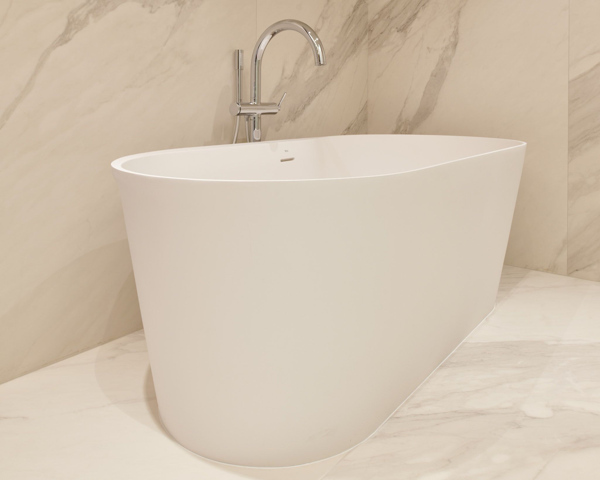 A modern bathroom with a freestanding bathtub, marble walls, and a sleek faucet.