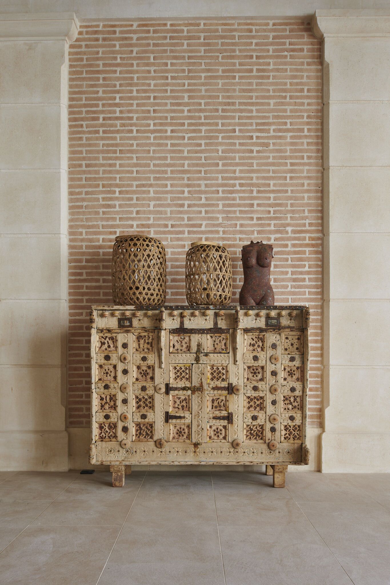 A wooden cabinet with intricate carvings and two decorative items on top.