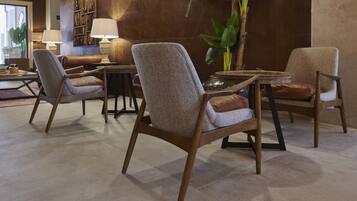 A modern lounge area with leather armchairs, a round table, and a large potted plant.