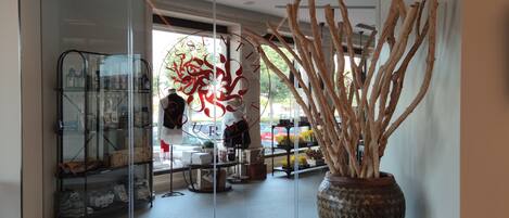 A modern interior with a large vase of branches, a glass display case, and a mannequin.