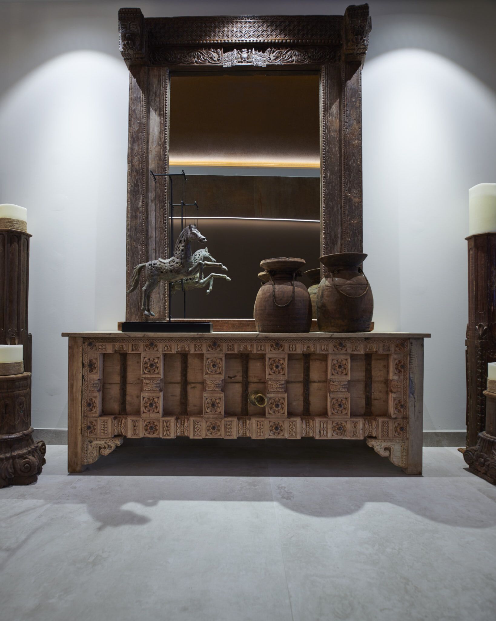 Un tocador de madera con un espejo, una escultura de caballo y dos piezas de cerámica.
