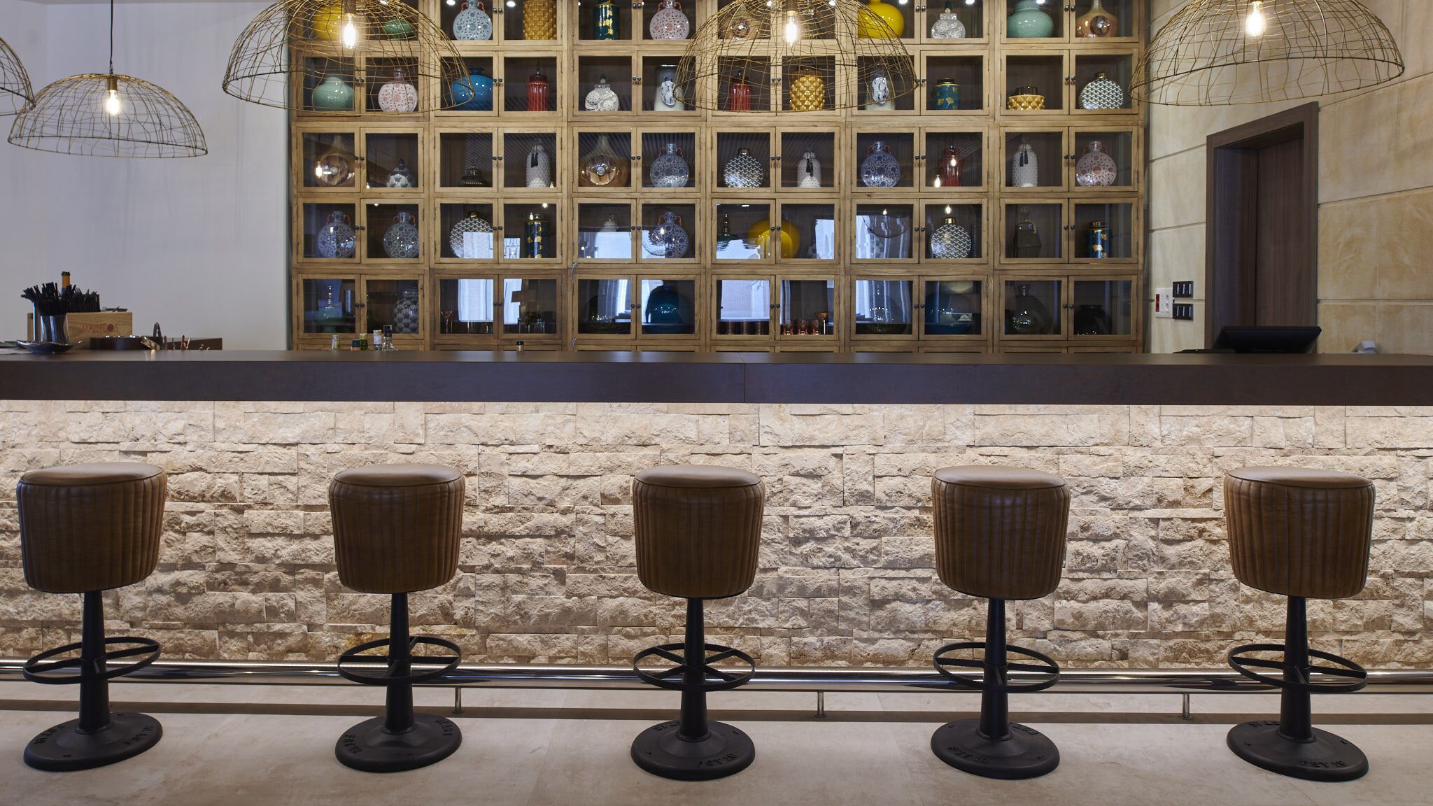Un espace bar avec un mur en pierre et de nombreux tabourets.