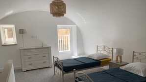 Ett sovrum med två sängar, en byrå, en lampa och ett fönster.