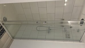 En dusch med glasväggar och modern design, utrustad med en kontrollpanel och ett duschmunstycke som kan hållas i handen.