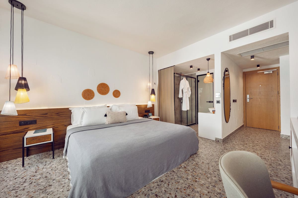 Relax in a spacious room with a large bed, bedside tables, and a wicker side table.