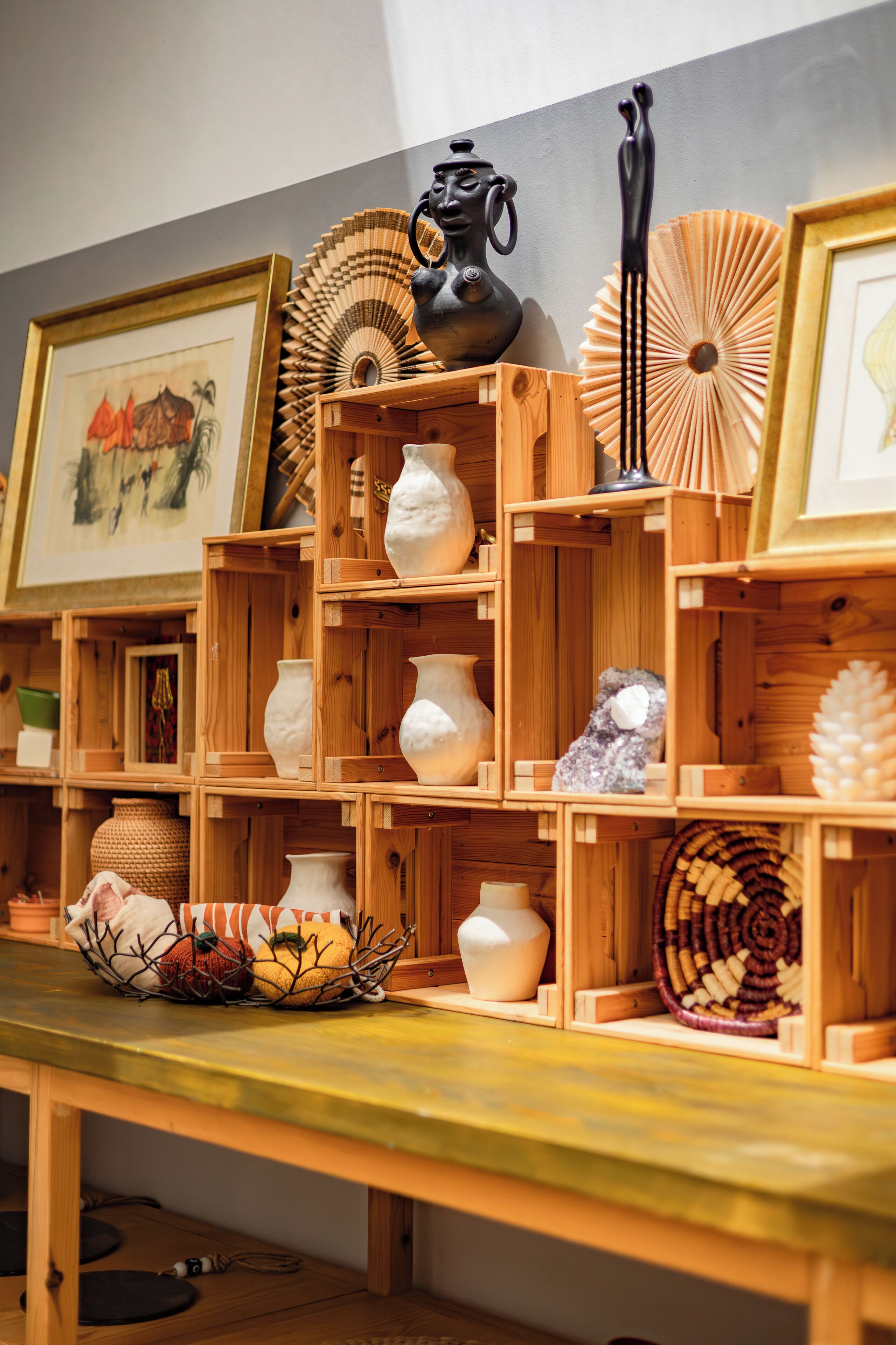 Exposição de diversos objetos de cerâmica e itens decorativos em caixas de madeira.
