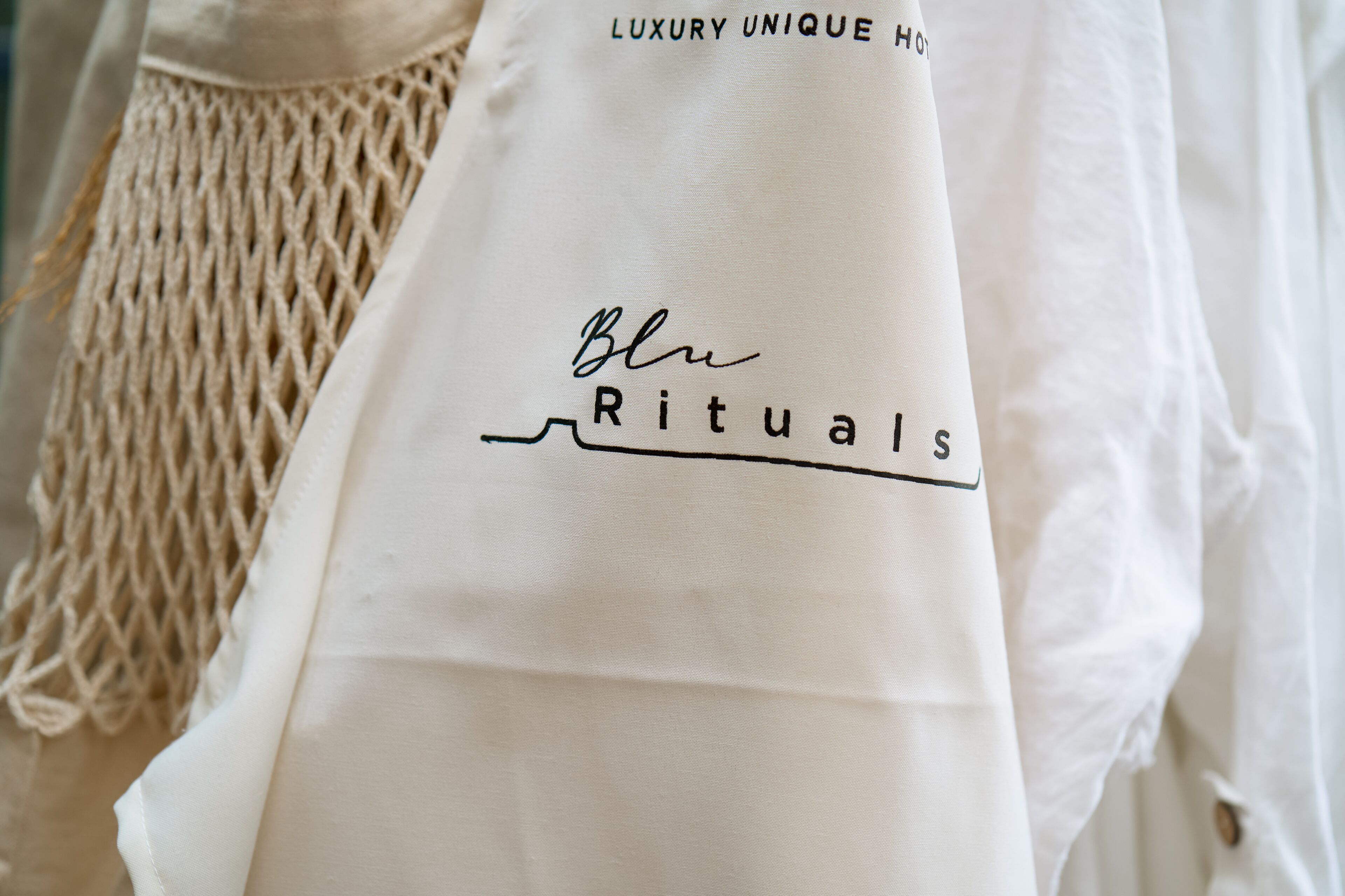 Tejido blanco con el texto "Blue Rituals" y "LUXURY UNIQUE".
