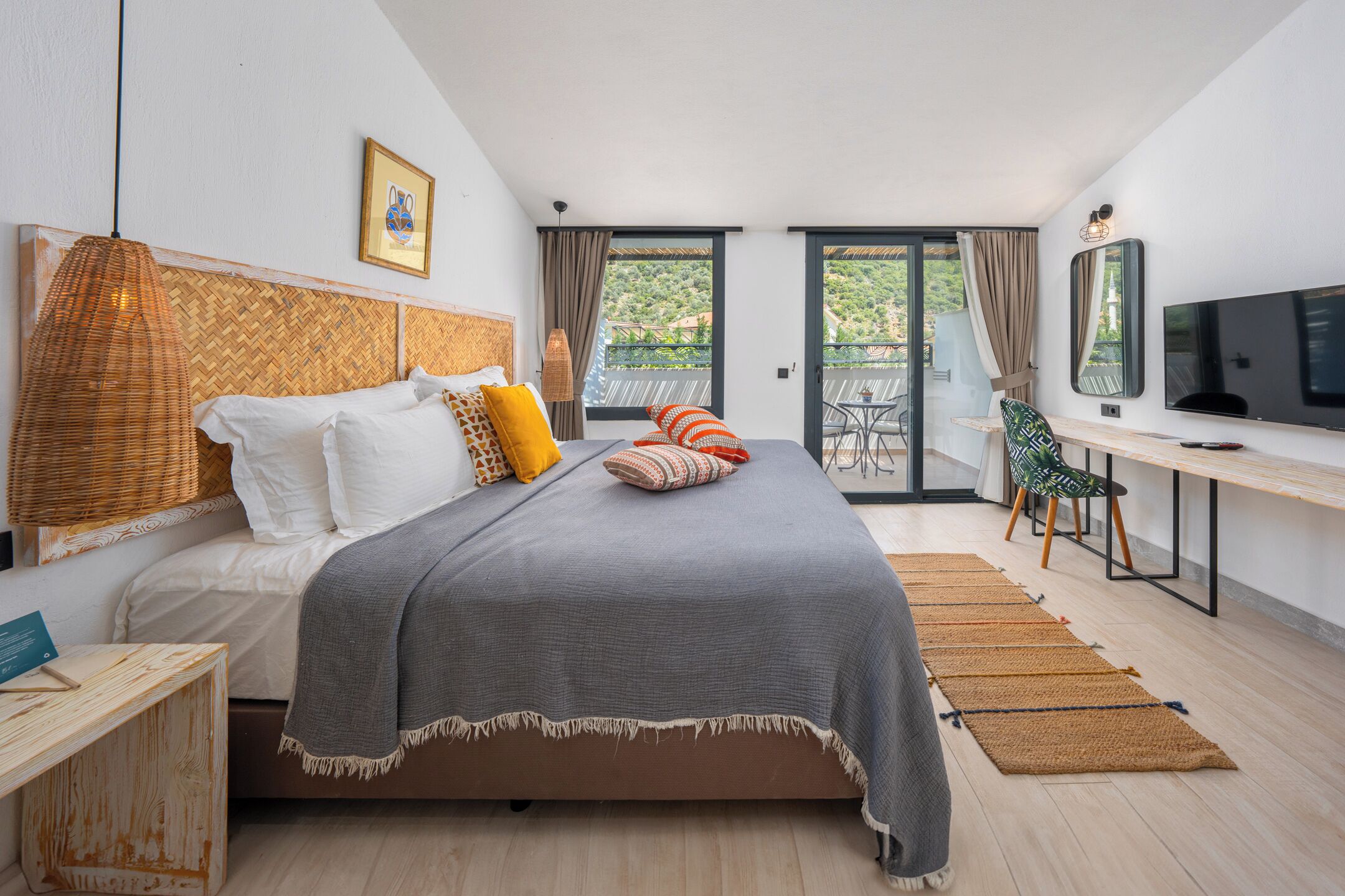 A bedroom with a bed, a desk, a TV, and a balcony with a chair.