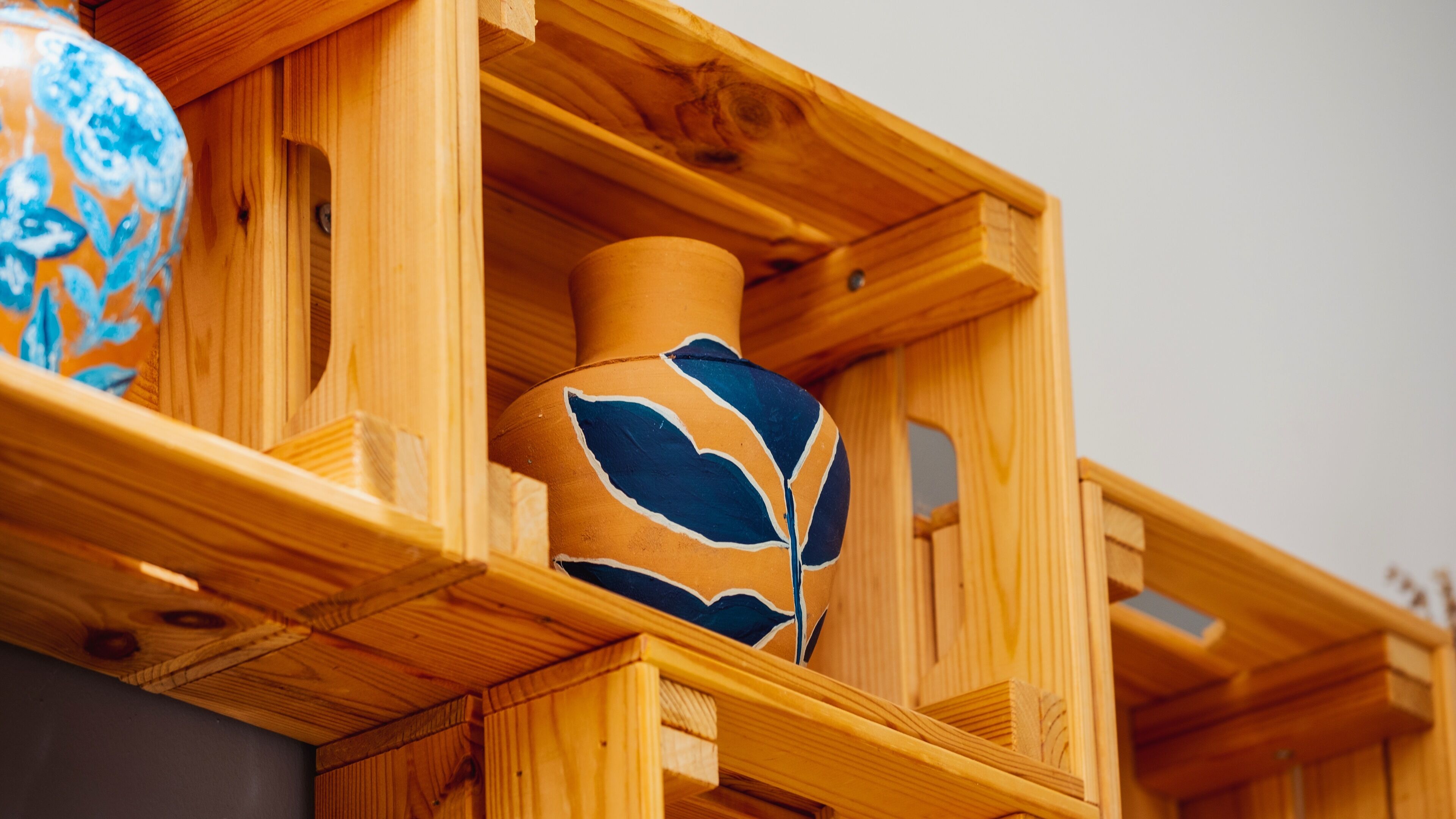 A wooden display case containing a ceramic vase with blue leaf patterns.