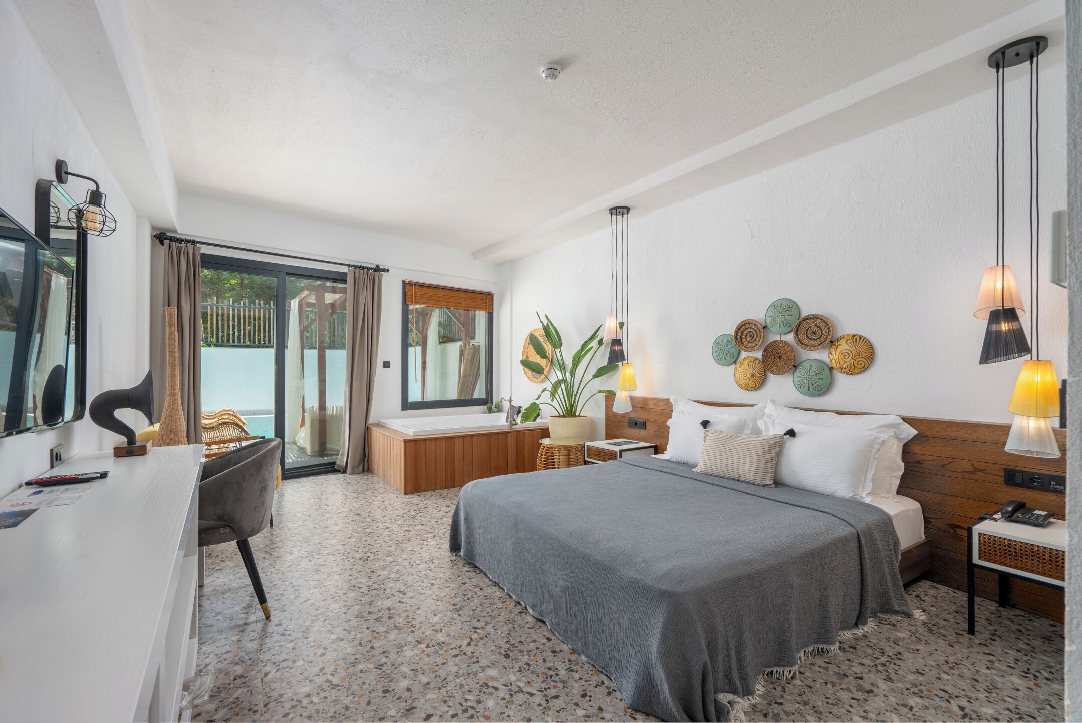 Een moderne slaapkamer met een groot bed, nachtkastjes, een bureau en een raam met gordijnen.