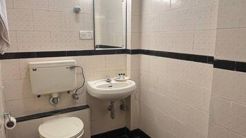 A small bathroom with a toilet, sink, and mirror.