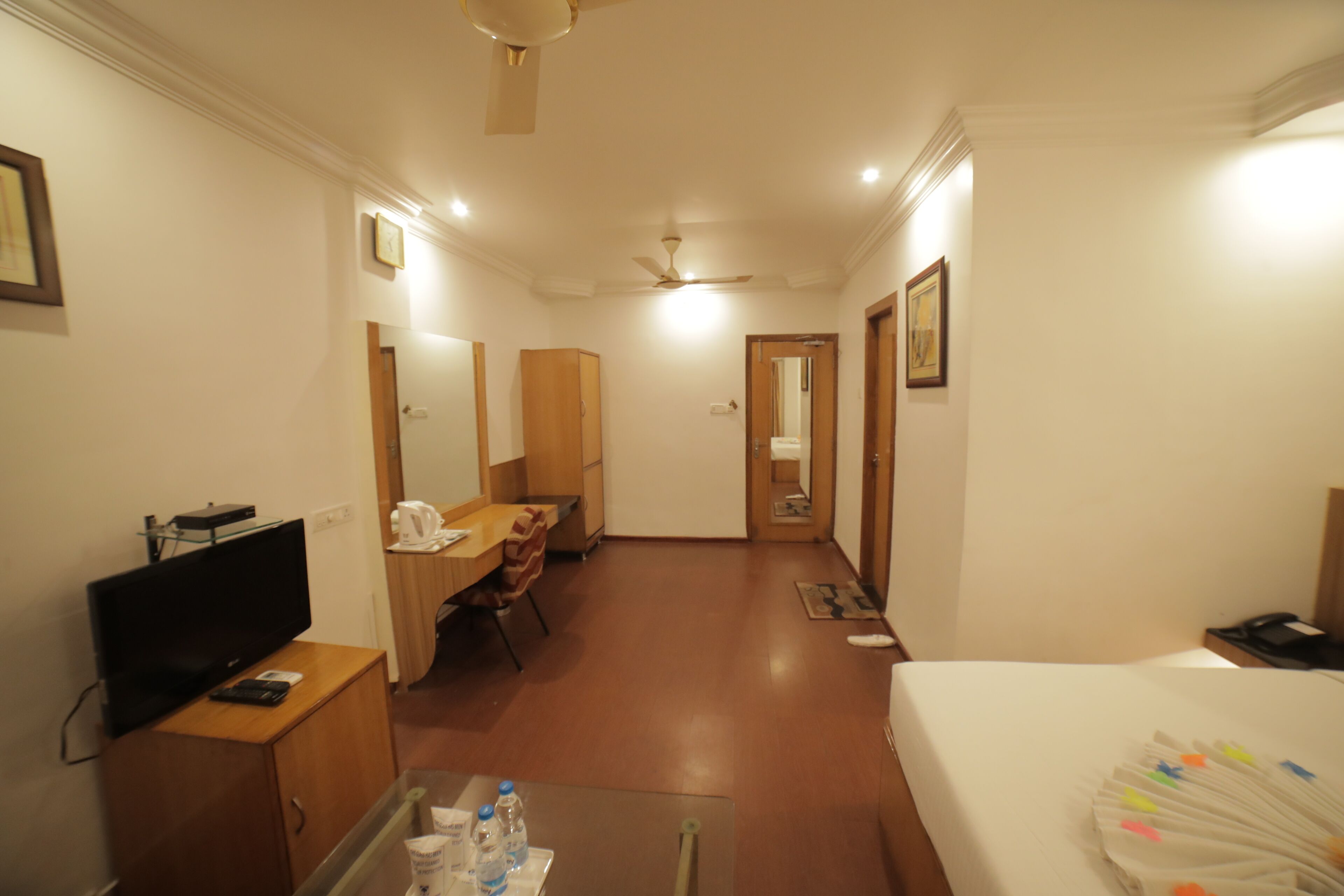 A hotel room with a bed, a desk with a chair, a television, and a wardrobe.