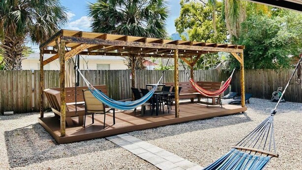 A wooden pergola with a hammock, patio furniture, and a covered seating area. - Experience the passion of hospitality, cleaning, and good location! (Tampa)