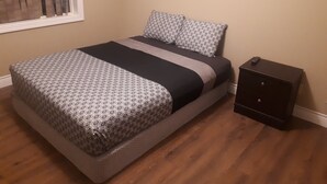 A bedroom with a bed, a nightstand, and a window with blinds.