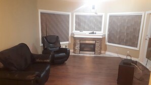 A living room with a fireplace, a black leather sofa, and a chair.