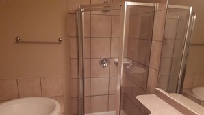 A bathroom with a glass-enclosed shower, a bathtub, and a sink.