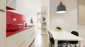 Eine moderne Küche mit roter Arbeitsplatte, weißen Schränken und einem Essbereich mit weißem Tisch und schwarzen Stühlen.
