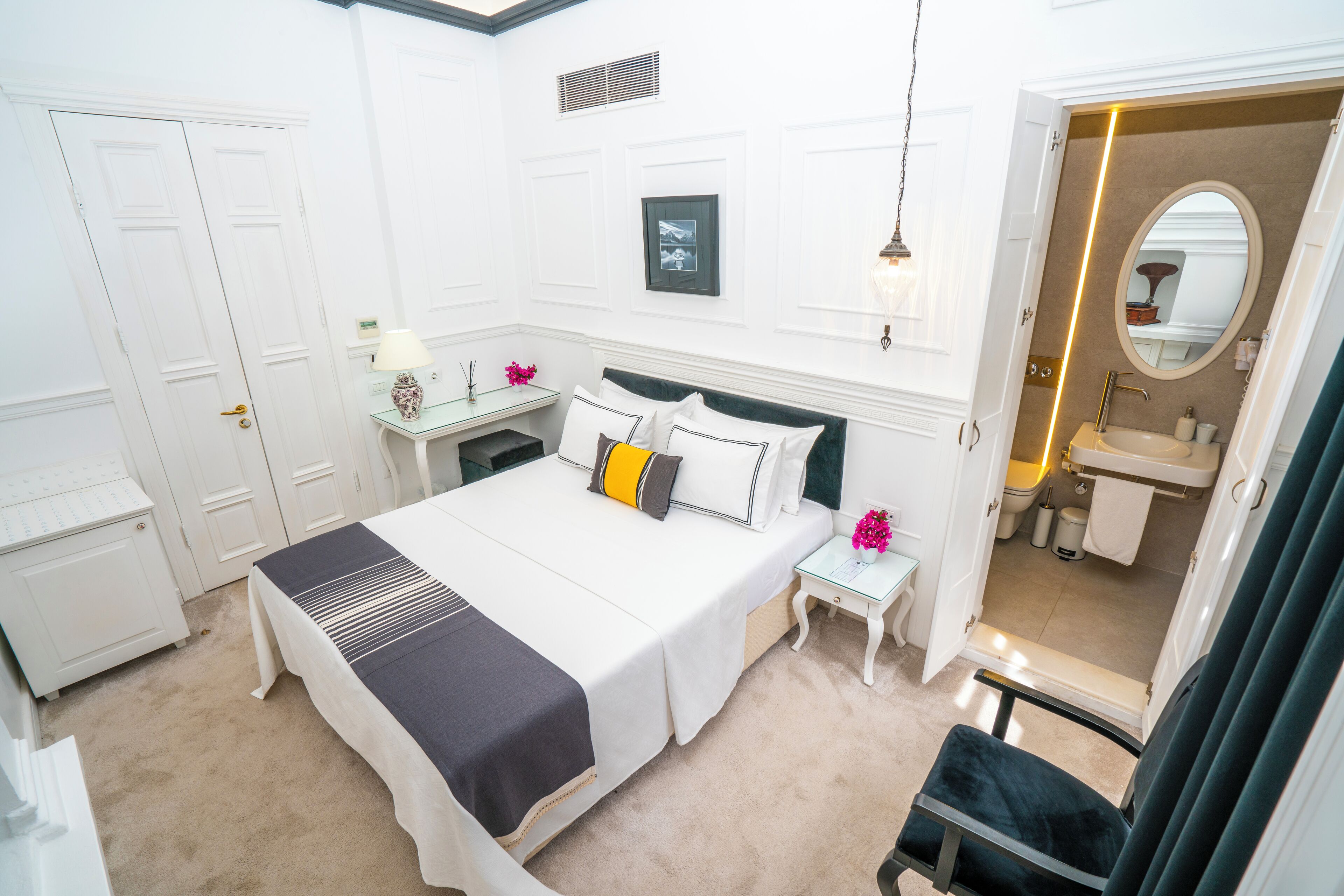 A hotel bedroom with a bed, bedside tables, a mirror, and a view into the bathroom.