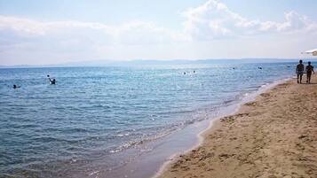 A beach with people swimming and walking along the shore.