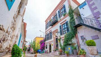 Uma rua de paralelepípedos estreita, ladeada por edifícios coloridos, alguns com varandas e plantas em vasos.