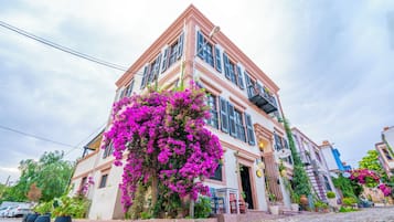 A corner building with a pink facade, a staircase, and a balcony.