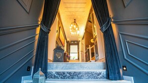 A grand staircase with a chandelier, leading to a door with a sign. - Siyah Lale Cunda 1841 (Ayvalik)