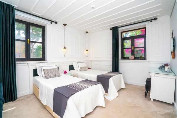 A room with two beds, a desk, and a window with curtains.
