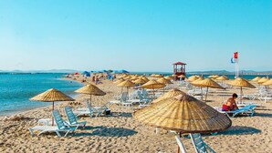 A beach with sun loungers and umbrellas, a lifeguard tower, and a flag. - Siyah Lale Cunda 1841 (Ayvalik)