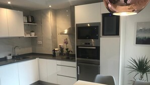 Eine moderne Küche mit weißen Schränken, Edelstahlgeräten und einem Essbereich mit Tisch und Stühlen.