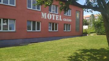 A red building with the sign "Motel Grado" and multiple windows.