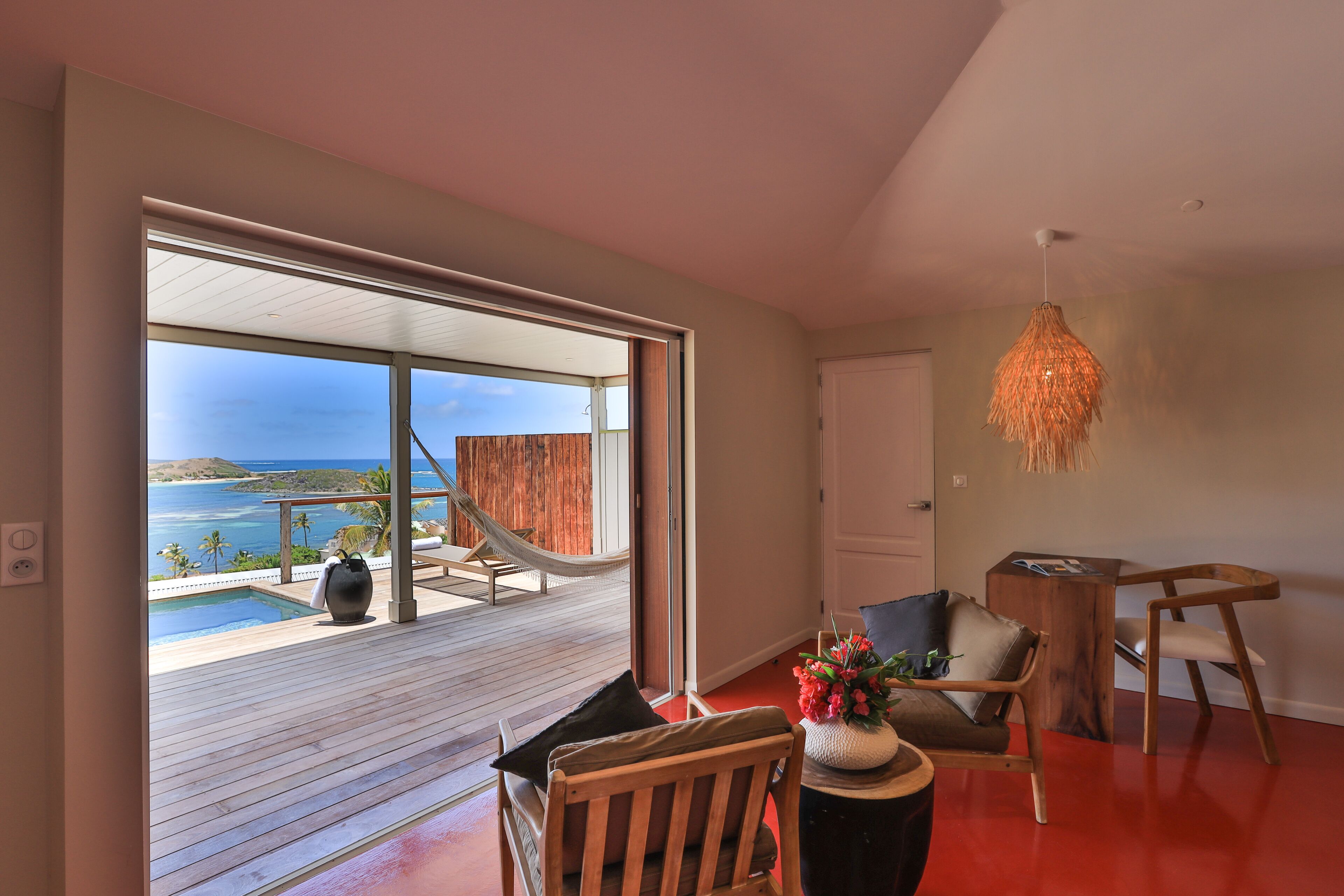 Decoração moderna com uma grande porta de correr de vidro que dá para uma varanda com piscina e vista para o oceano.