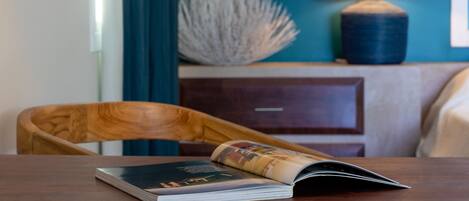 A room with a wooden table, a chair, a lamp, a nightstand, and a bed.