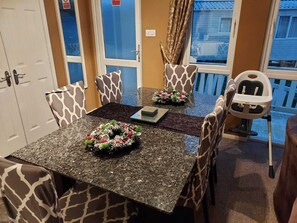 Un comedor con una mesa de granito, sillas estampadas y vistas a un balcón.