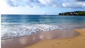 Una playa con agua cristalina, orilla arenosa y huellas.